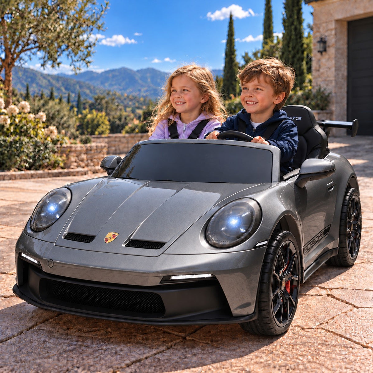 Gray Porsche 911 GT3 24V Kids 2 Seater Ride-On Car, Boy and Girl Driving on a Villa Driveway