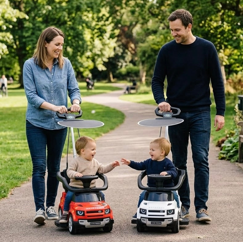 Lifestyle Photo of Red and White Land Rover Defender Push Cars for Toddlers with Sunshade Canopy and Parent Handle, Two Kids Riding in the Park with Mom and Dad