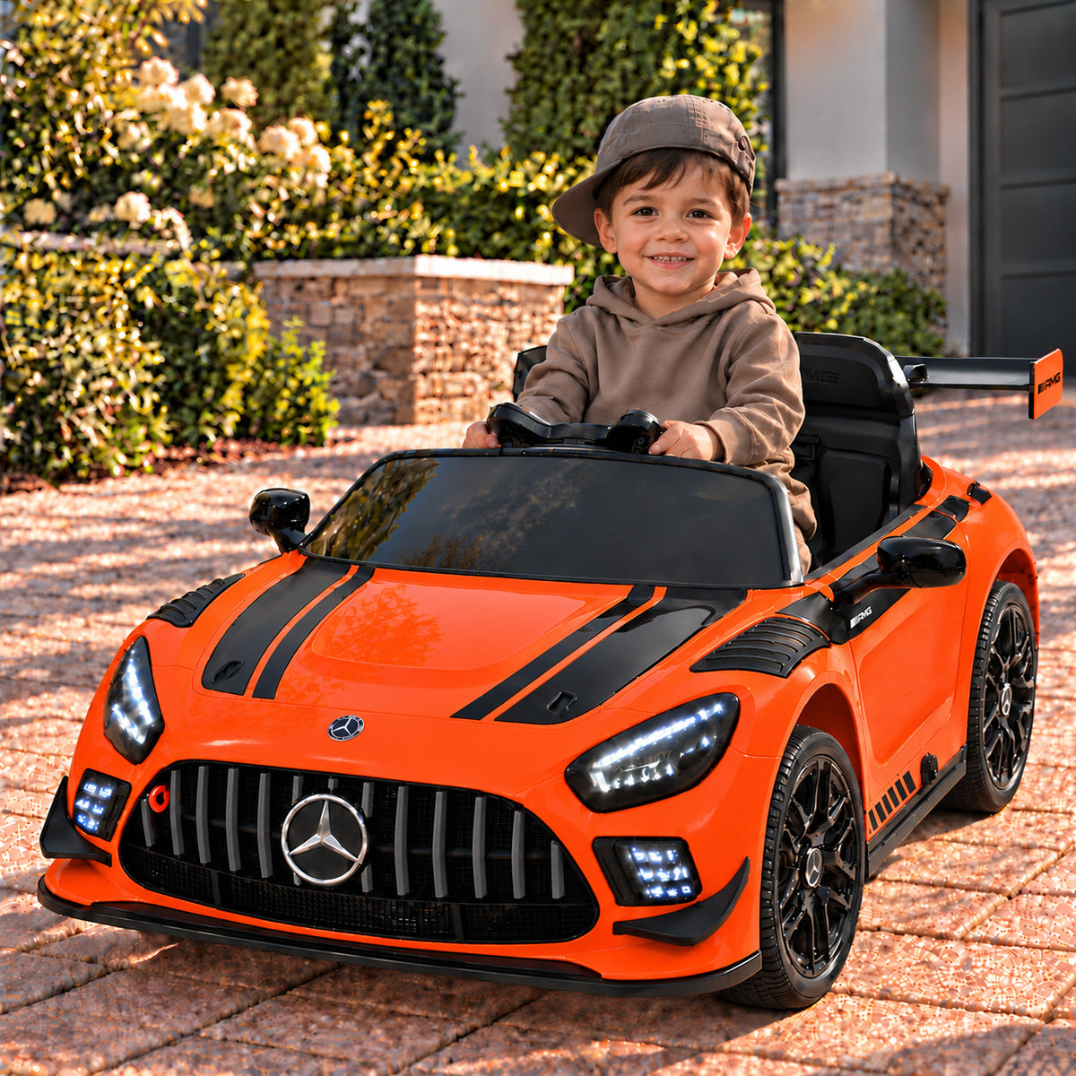 Orange Mercedes AMG GT3 EVO 12V Kids Ride-On Car with Parental Remote, Boy Driving on a Driveway