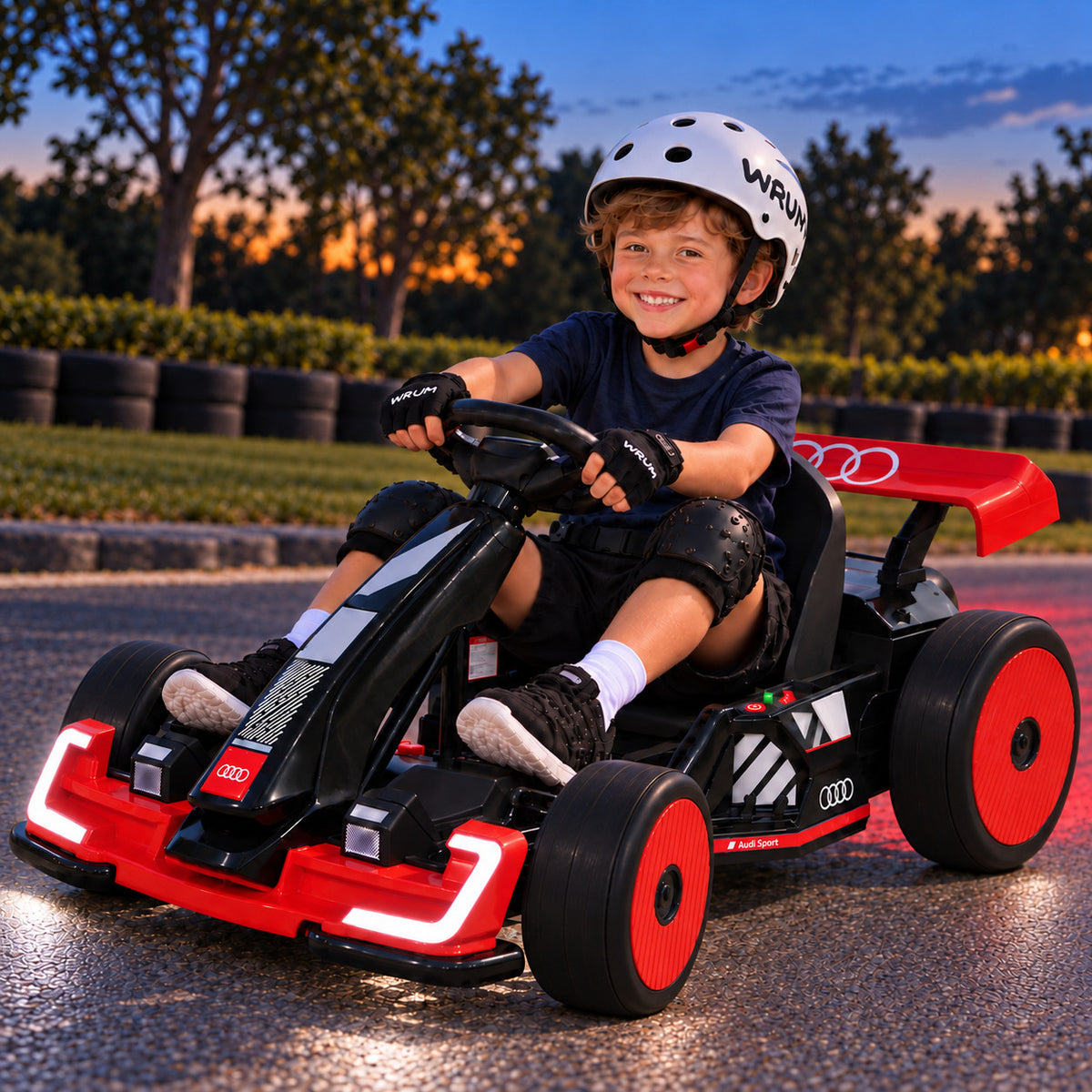 Red Audi Sport 24V Kids Drift Go Kart with Glowing LED Lights, Driven by a Smiling Boy on a Track at Sunset
