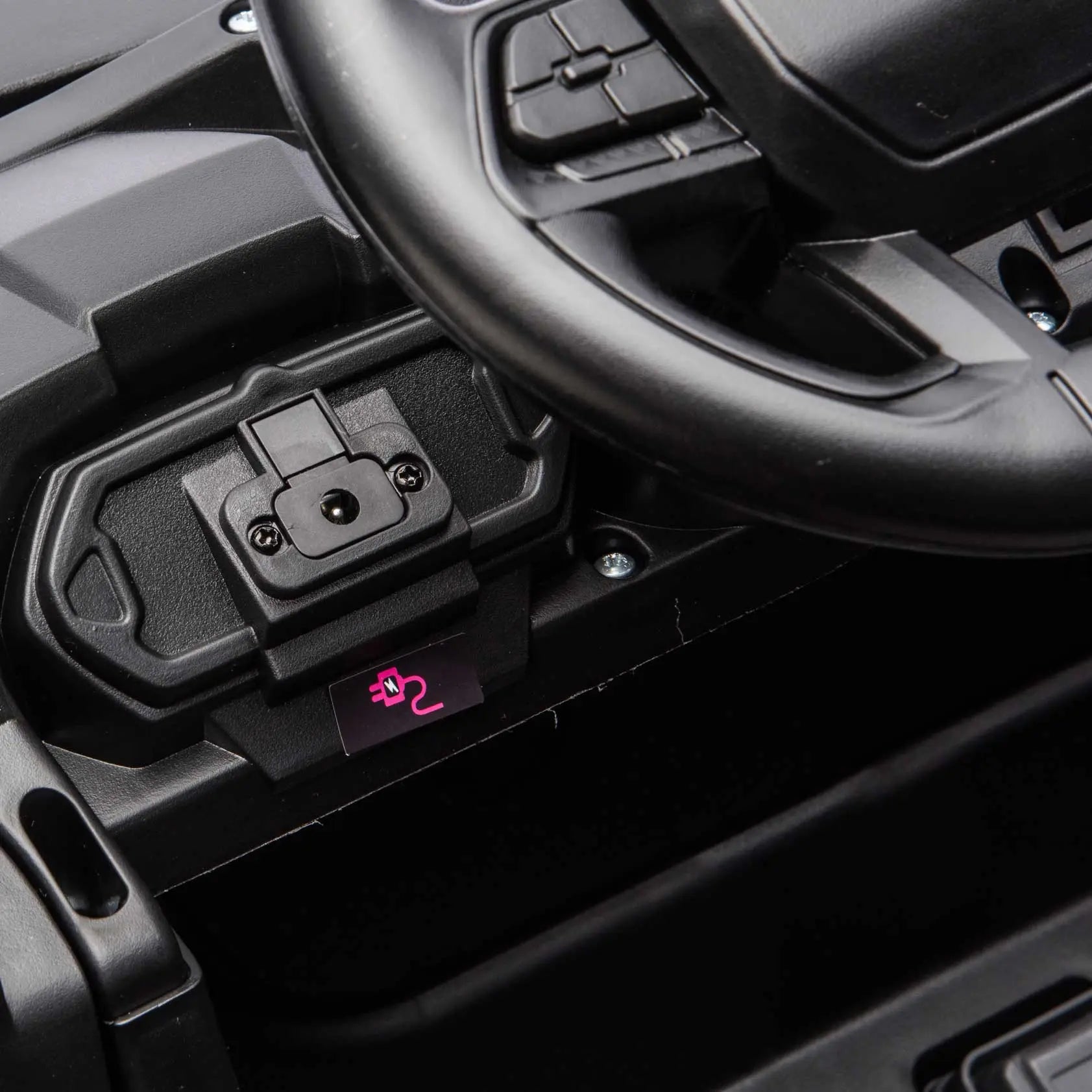 Close-up of the Trail Rider 24V 4WD kids ride-on UTV dashboard showing steering wheel and built-in charging port.