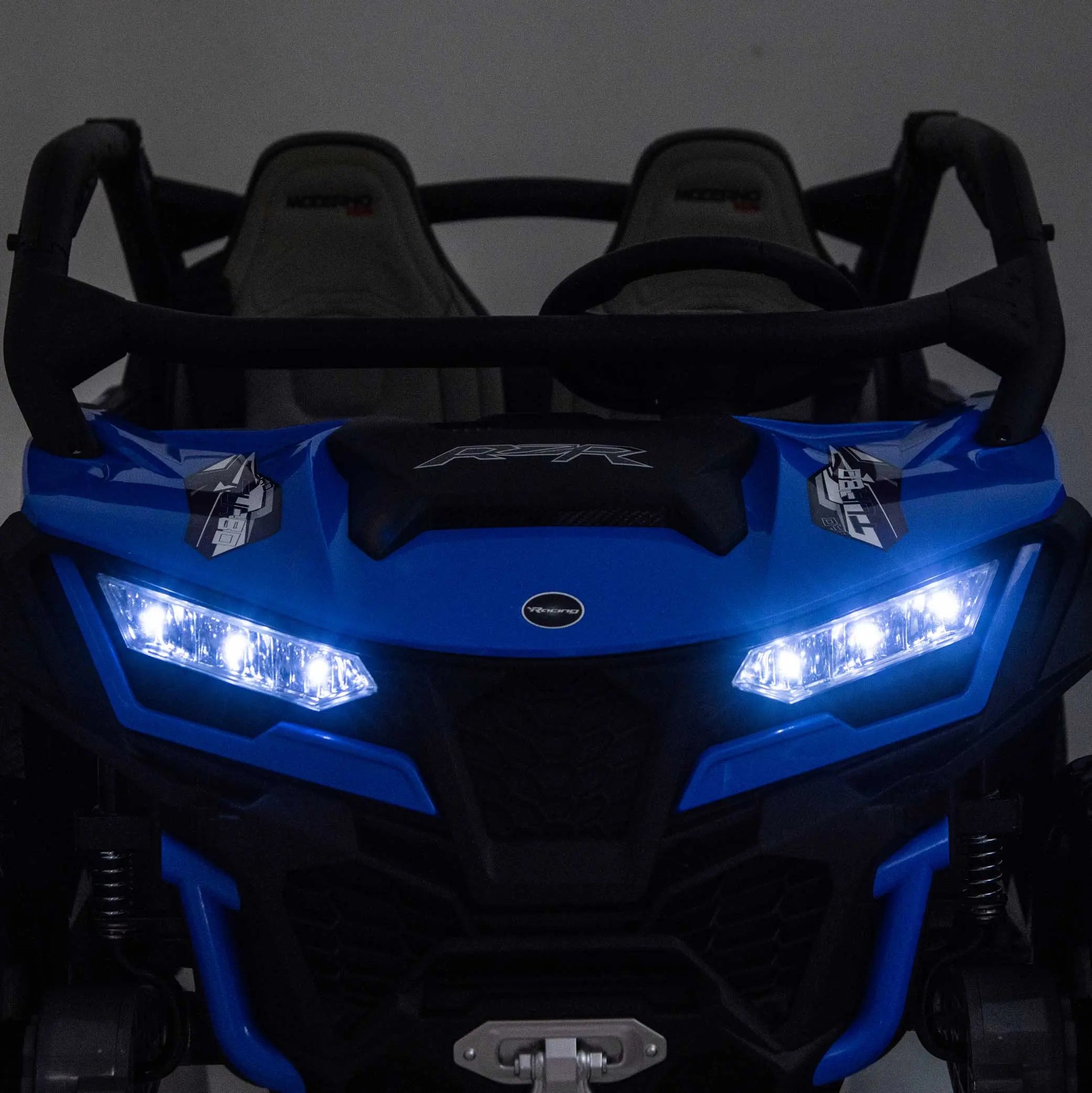 Blue Trail Runner 24V 4WD kids electric ride-on UTV with LED headlights illuminated, front close-up view