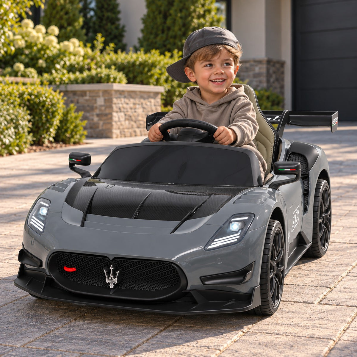 Gray Maserati GT2 24V Kids Ride-On Car, Boy Driving on a Villa Driveway