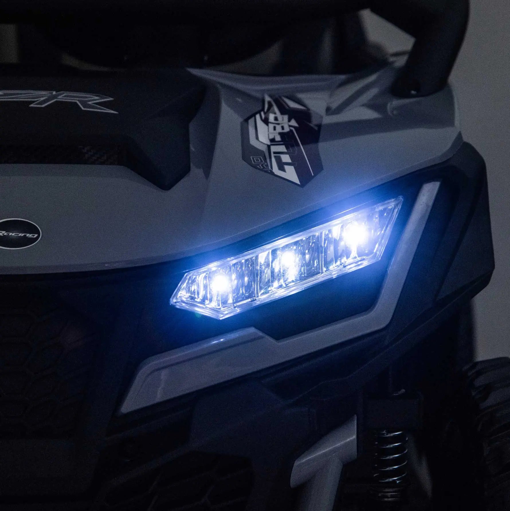 Gray Trail Runner 24V 4WD kids electric ride-on UTV with LED headlights illuminated, front close-up view-2