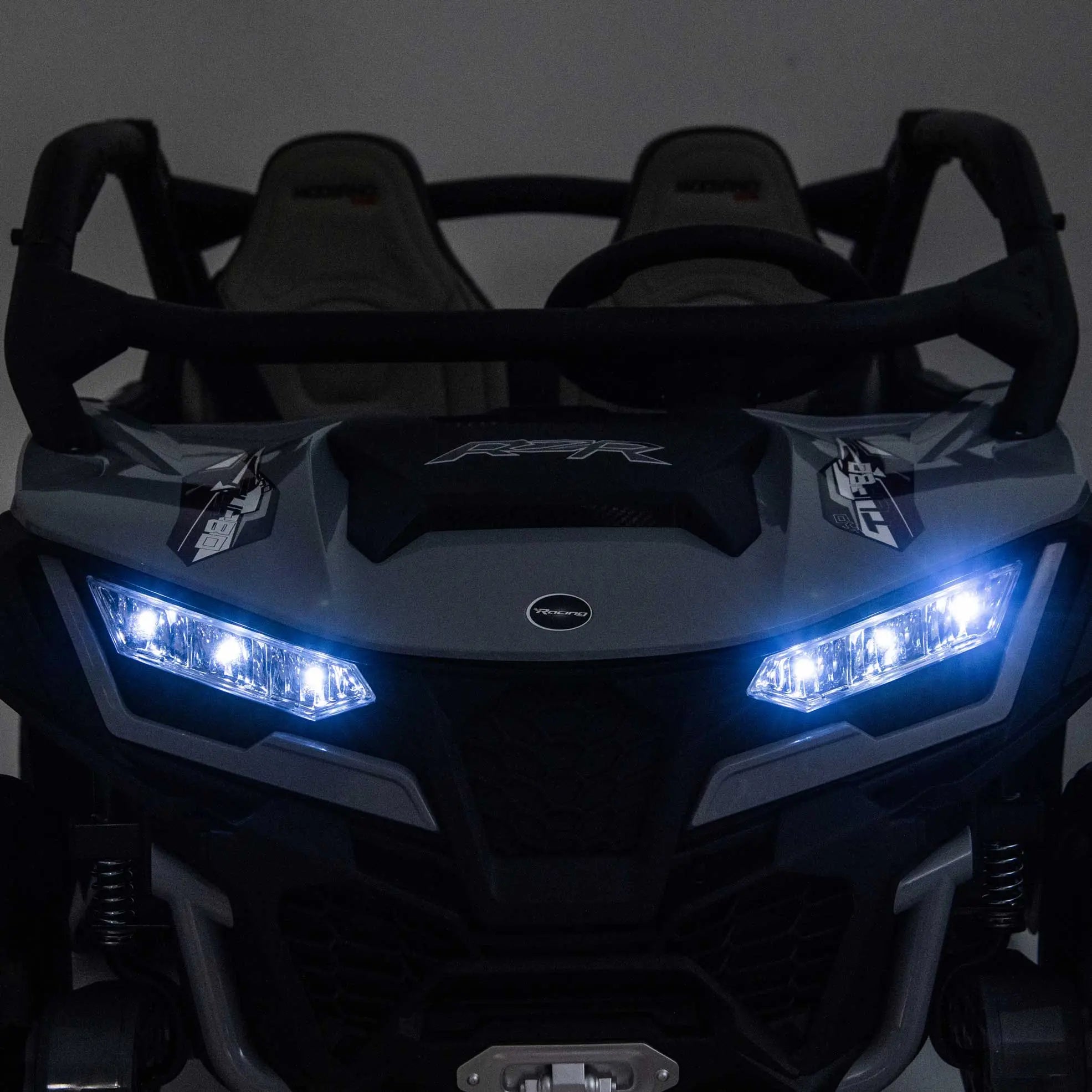 Gray Trail Runner 24V 4WD kids electric ride-on UTV with LED headlights illuminated, front close-up view