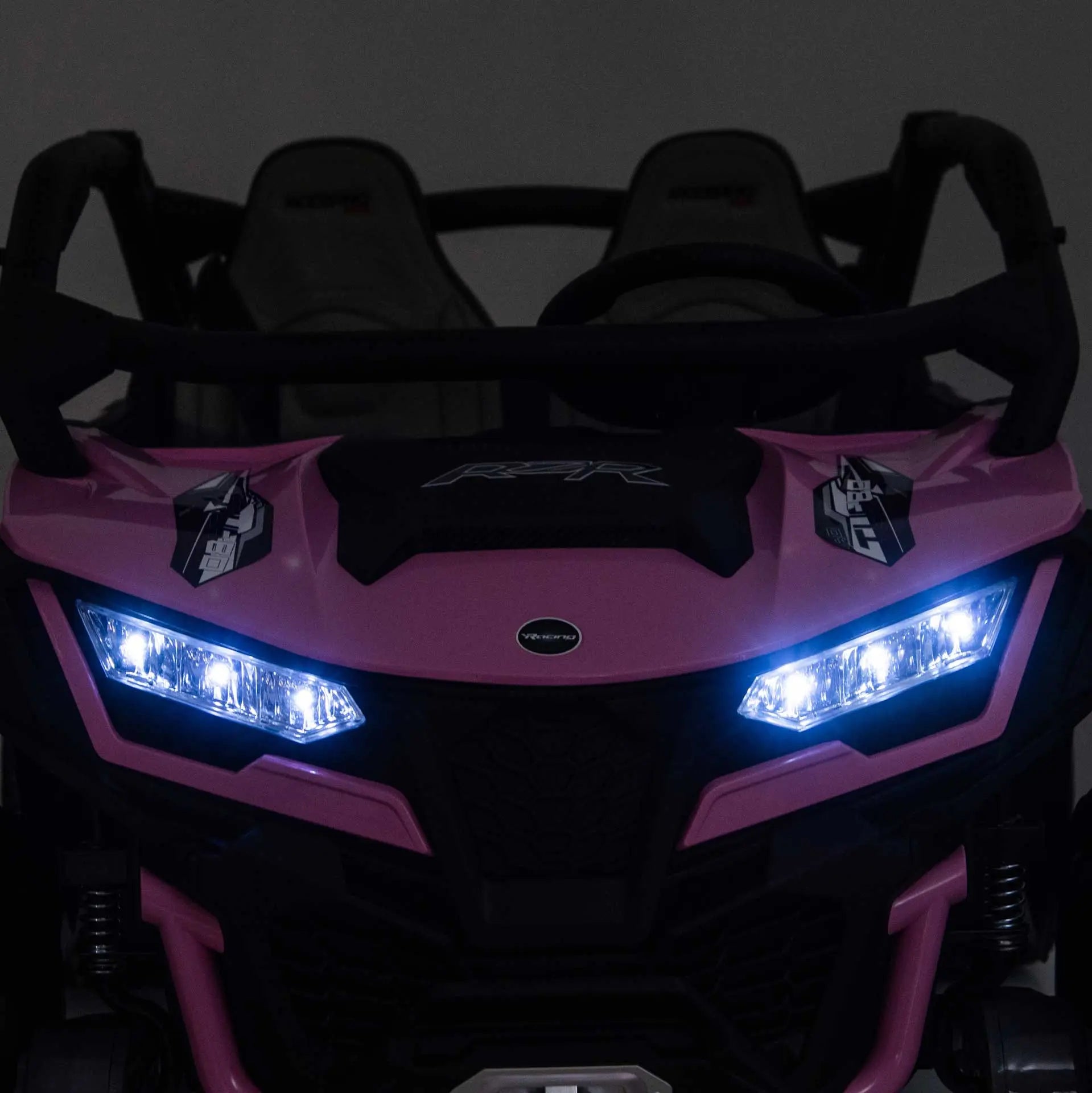 Pink Trail Runner 24V 4WD kids electric ride-on UTV with LED headlights illuminated, front close-up view