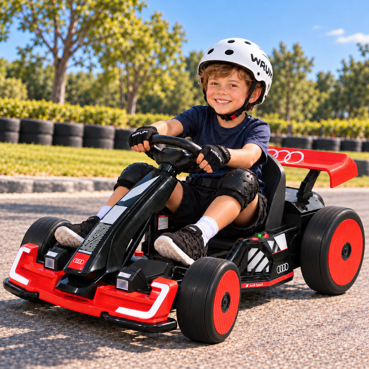 Boy in a Helmet Driving the Red Audi Sport 24V Electric Drift Go Kart for Big Kids on a Sunny Race Track