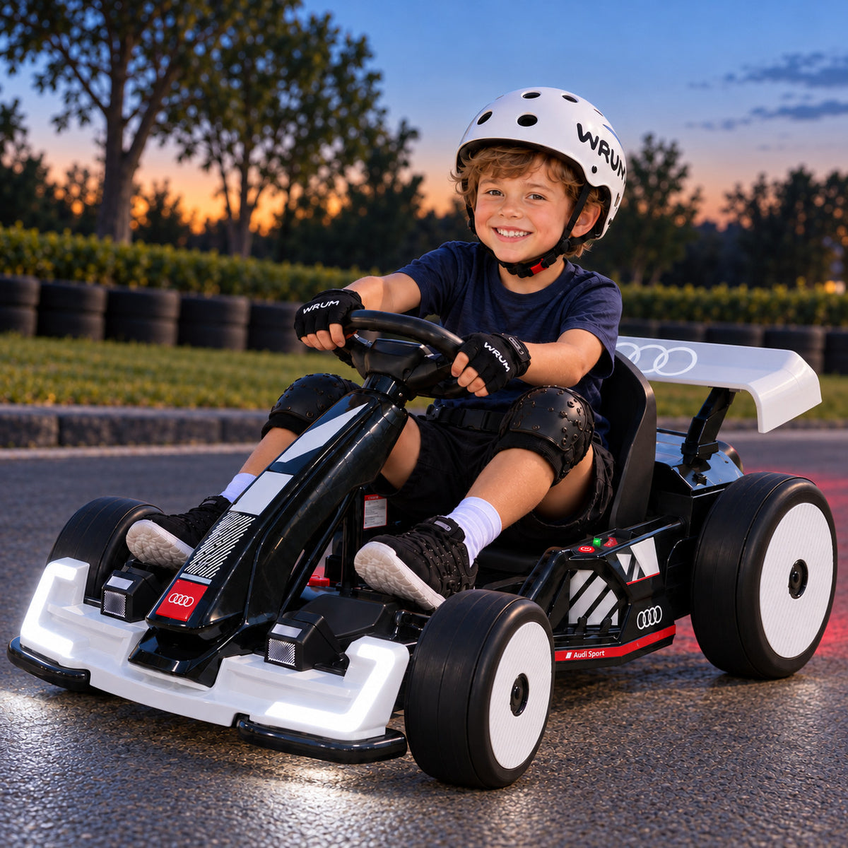 White Audi Sport 24V Big Kids Drifting Go Kart with LED Headlights On, Driven by a Boy on a Track at Dusk