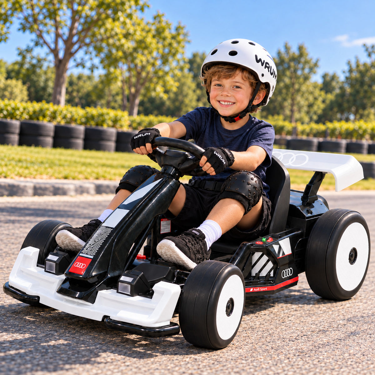 Smiling Boy Riding the White Audi Sport 24V Electric Go Kart for Big Kids on a Sunny Outdoor Race Track